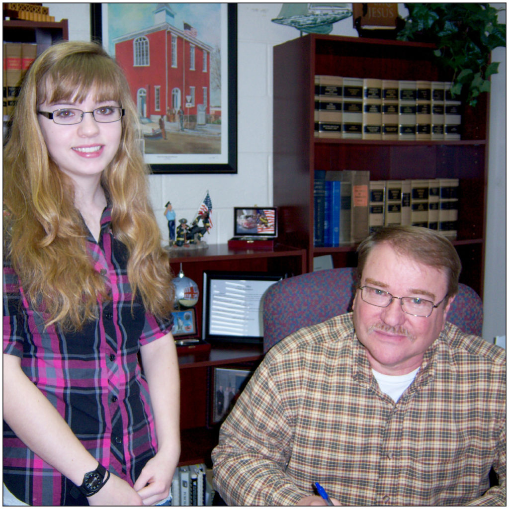 CTE MONTH-County Mayor Dale Reagan (seated) recently signed a proclamation designating February 27 as Career Technical Day in Clay County as Bonnie Craighead (standing), active Career Technical Education student at Clay County High School, looks on.